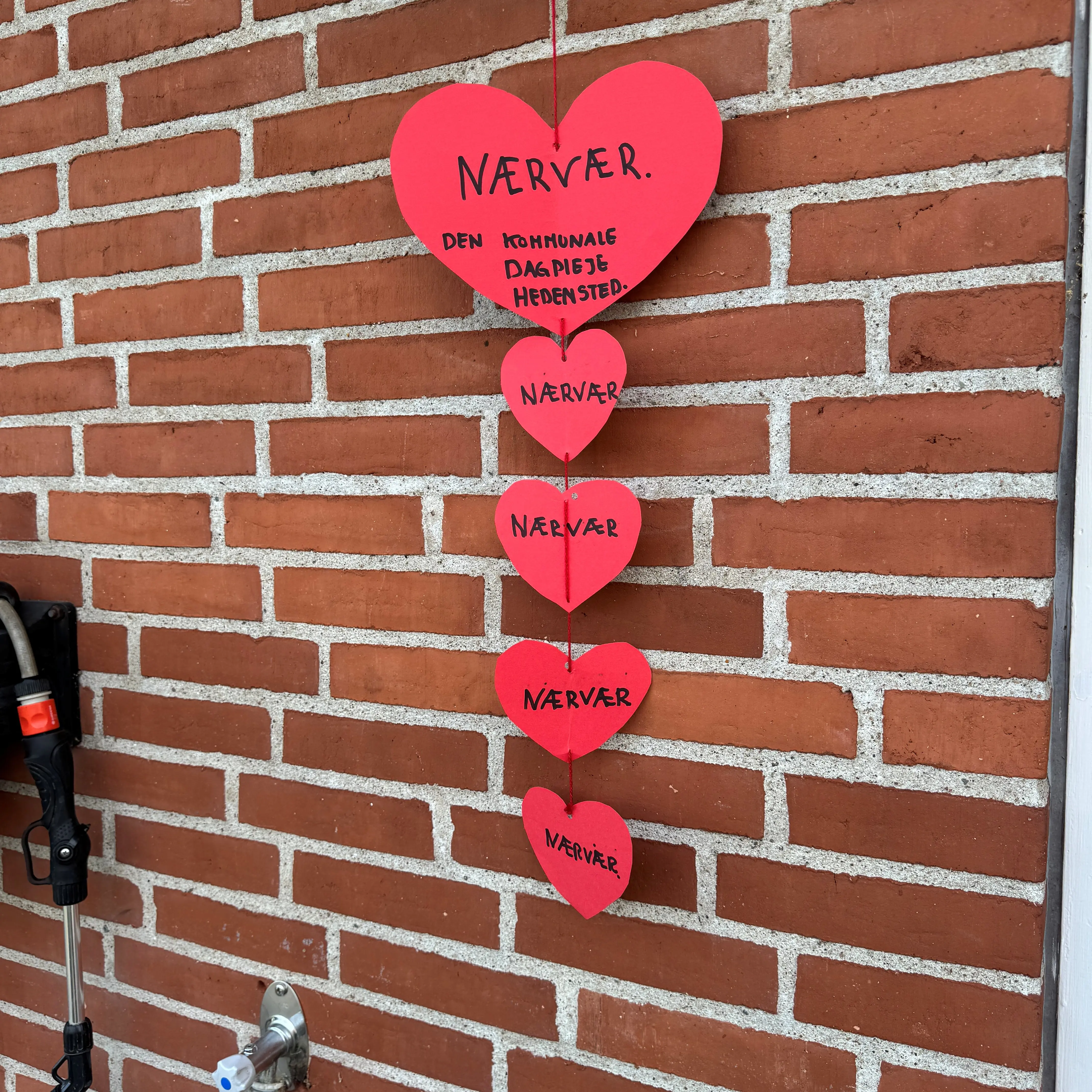 Hjerter med 'nærvær' skrevet i hænger på mur